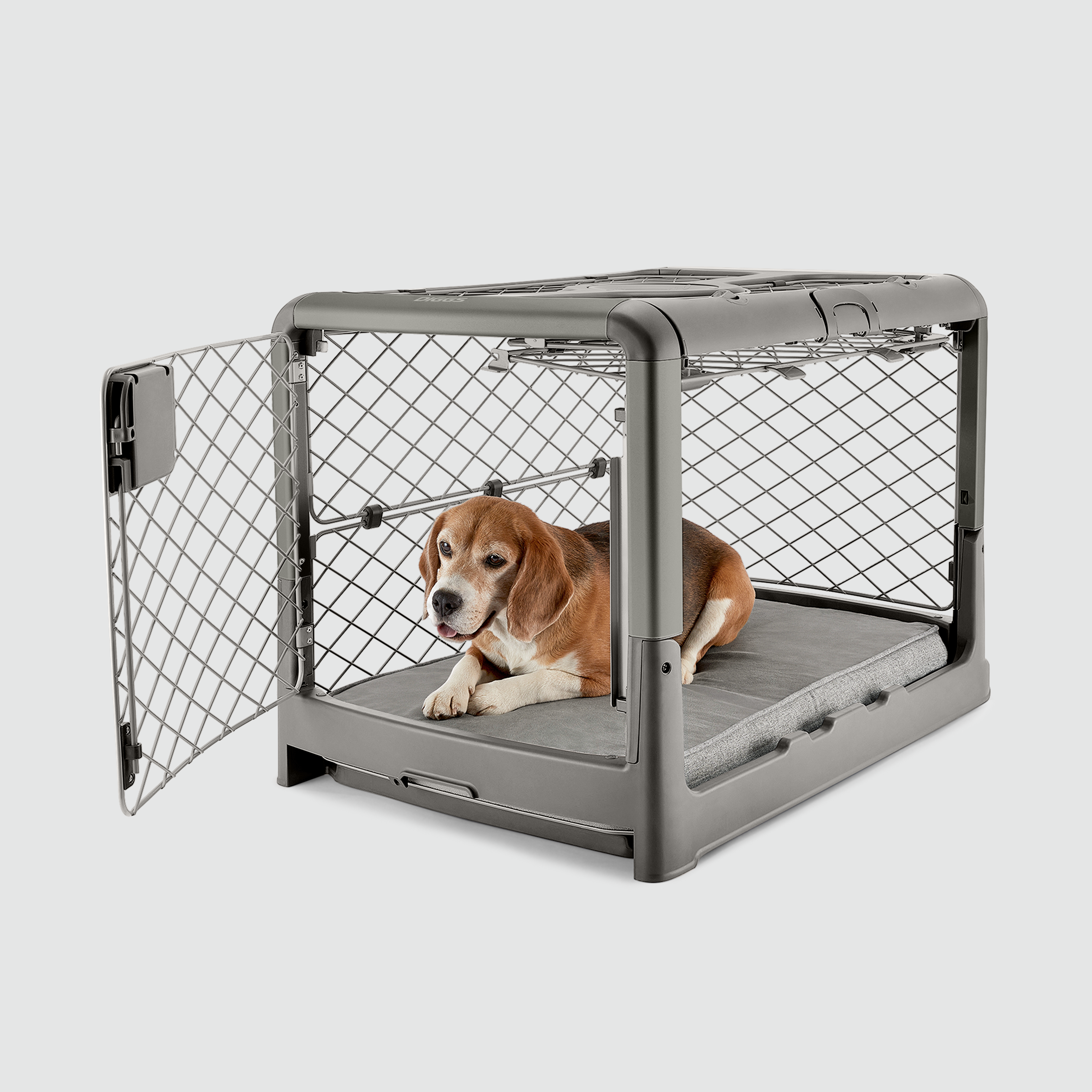 A dog sitting in a Revol crate with open front and side doors